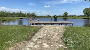 A wooden dock extending into a calm lake, surrounded by grassy banks and trees. - Escape to Calcasieu Lake Lodge-Premier Fishing and Family Getaway (Lake Charles)