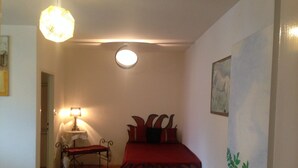 A bedroom with a bed, a nightstand, a lamp, and a painting on the wall.