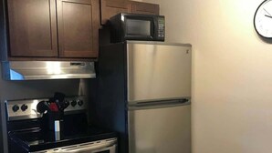 Una cocina con electrodomésticos de acero inoxidable, armarios de madera y un microondas.