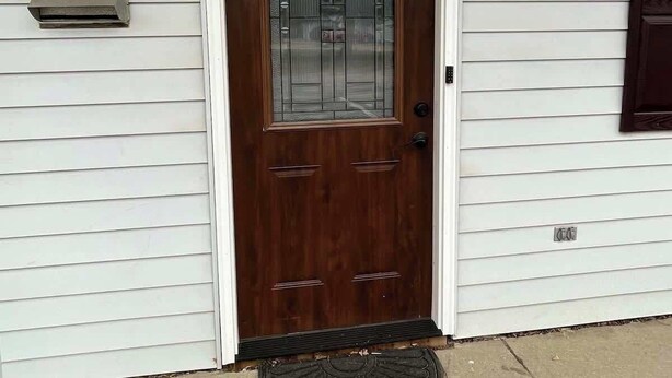Una puerta principal con un panel de vidrio, un buzón y una lámpara arriba.