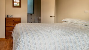 A bedroom with a bed, a wooden dresser, a door, and a window. - A delightful studio in idyllic Mapua Village, perfect from which to explore the Tasman region (Mapua)