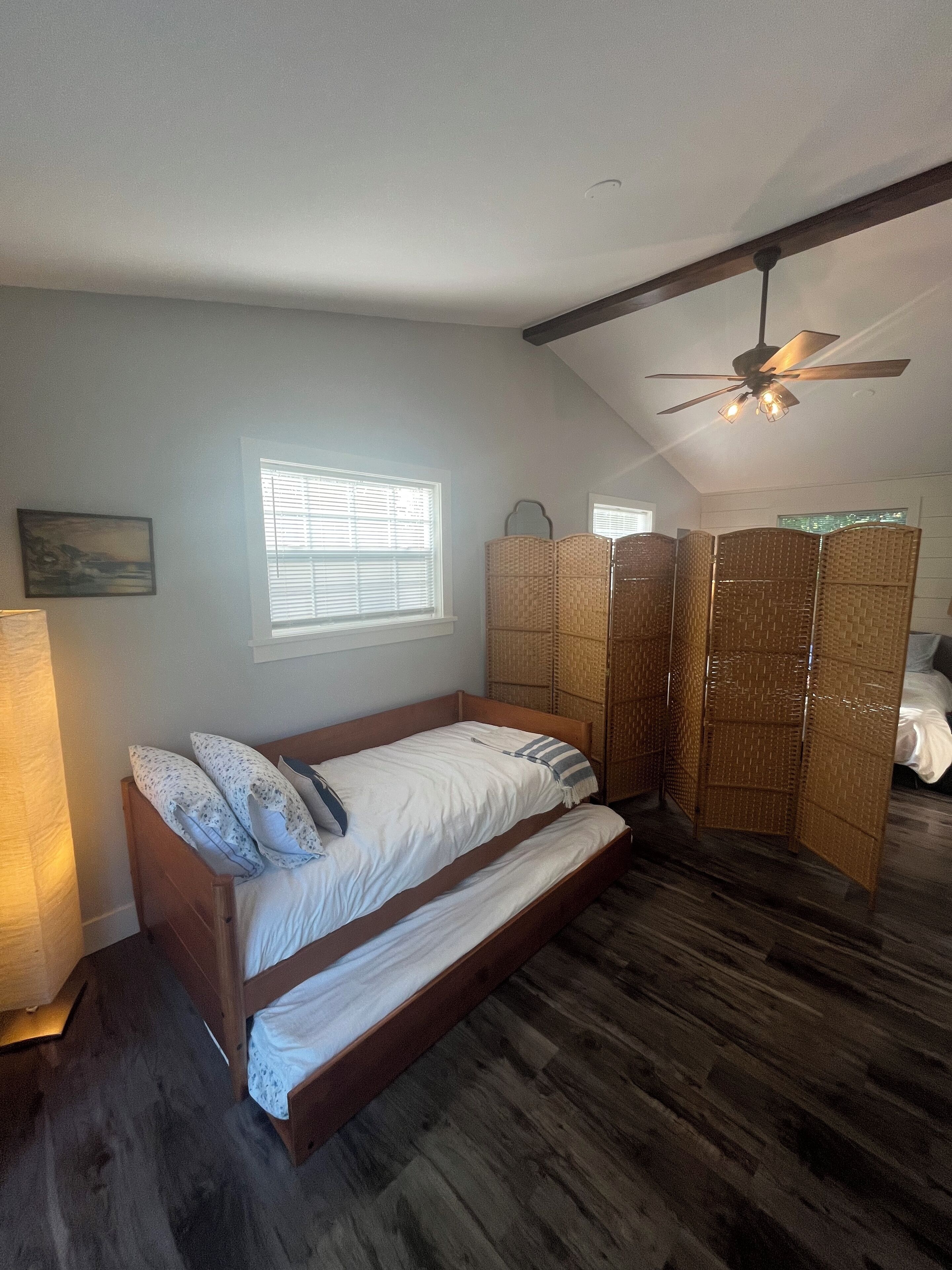 Un dormitorio con cama de madera, ventilador de techo y ventana con persianas.