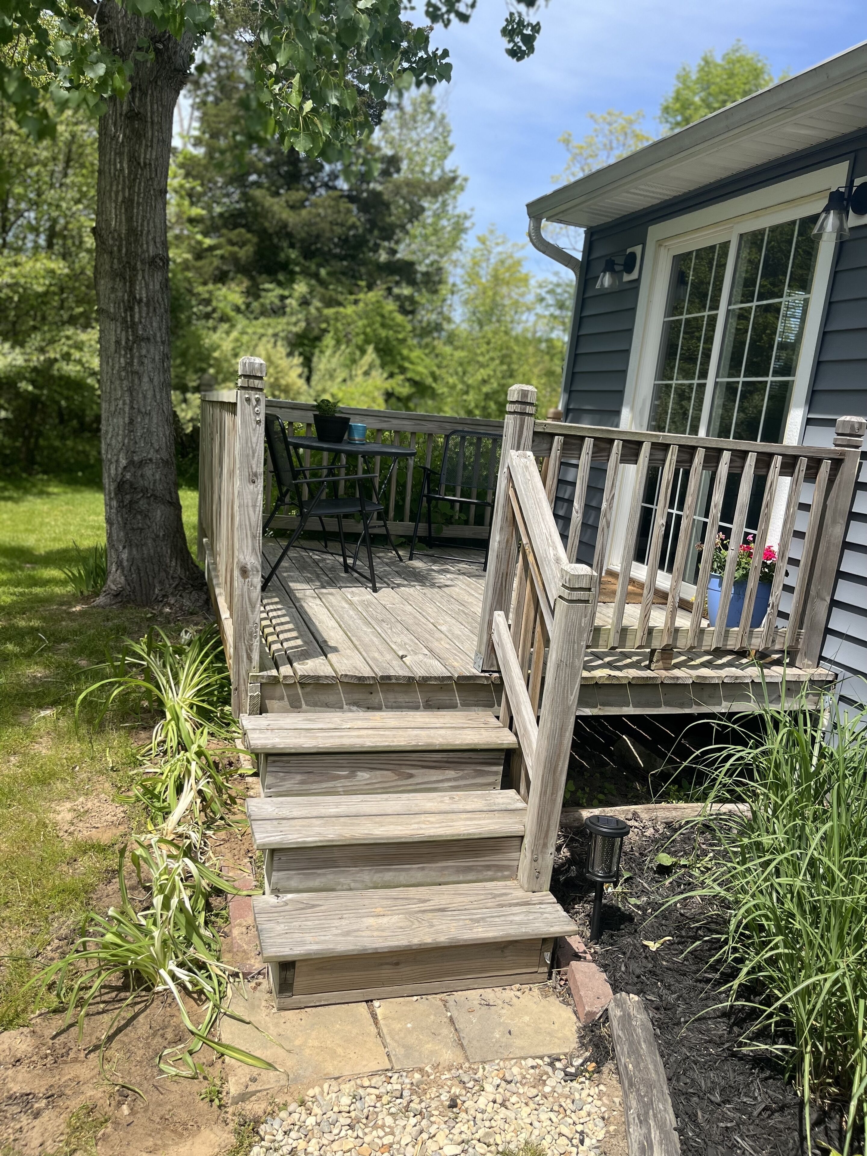 A wooden deck leading to a house with a window and a door.