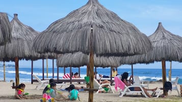 Een privéstrand, ligstoelen aan het strand, parasols, strandlakens