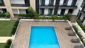 Une piscine sur le toit, avec une eau d’un bleu limpide, entourée de chaises longues et de verdure.