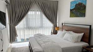 Une chambre d’hôtel avec un grand lit, une tête de lit en bois, un tableau au mur et une fenêtre avec des rideaux.