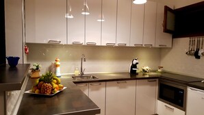 A modern kitchen with white cabinets, stainless steel appliances, and a fruit bowl on the counter. - Luxury and functional sea view apartment (Los Gigantes)