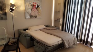A compact bed with a mattress and pillows, a grey chair, a floor lamp, and a painting on the wall. - Luxury and functional sea view apartment (Los Gigantes)