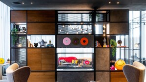 A modern interior with a large window, a wall-mounted shelf with decorative items, and two armchairs.
