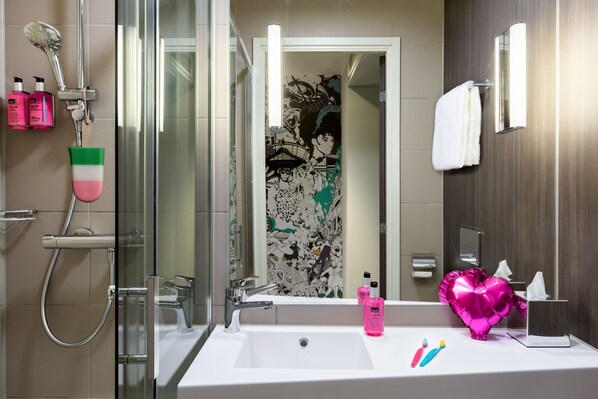 Un baño con un lavabo blanco, un espejo, una ducha con cabezal de ducha de mano y un perchero para toallas.