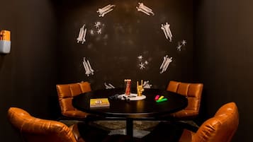 A conference room with a round table, brown leather chairs, and a wall with a space-themed mural.