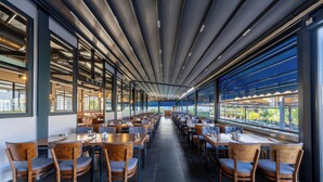 A spacious restaurant with long tables and chairs, large windows offering views of the outdoors, and a modern ceiling design. - Palmora Lara Hotel - All inclusive (Antalya)