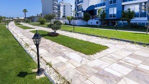 A modern multi-story hotel with balconies, a well-maintained lawn, and a clear sky. - Palmora Lara Hotel - All inclusive (Antalya)