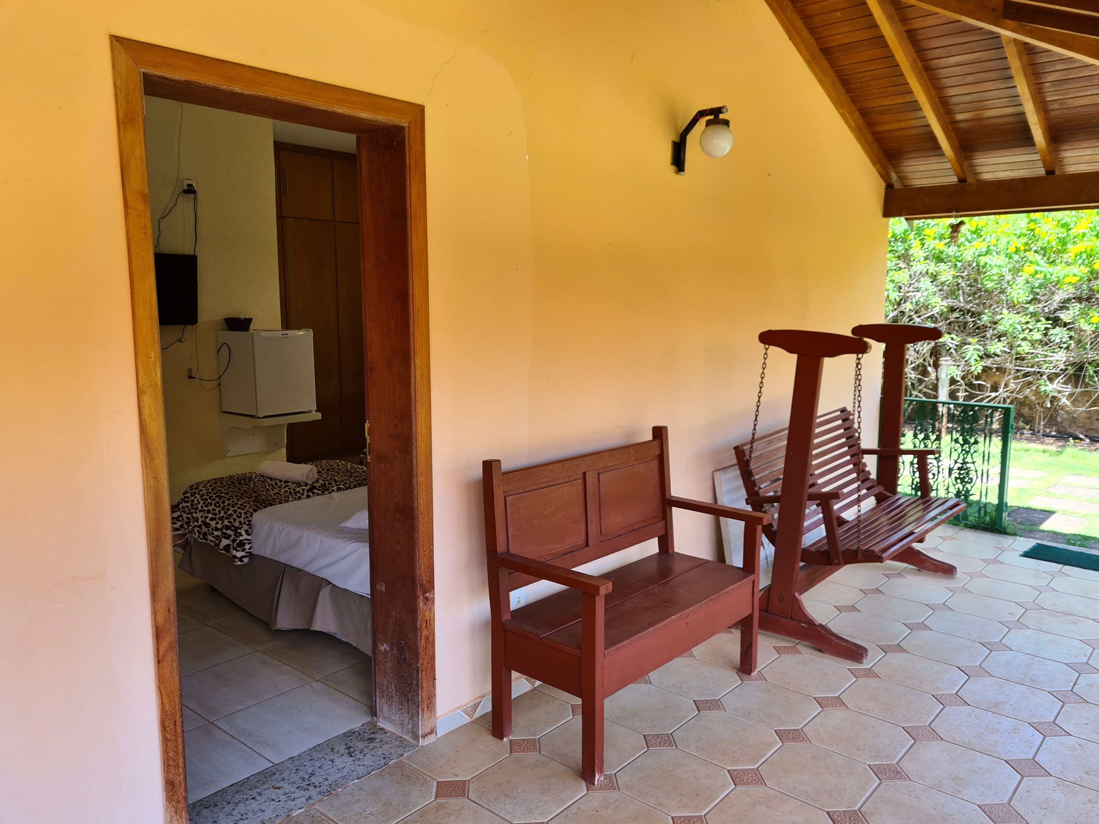 A room with a bed, a wooden bench, and a small table.
