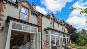 A two-story building with a patio area featuring outdoor seating and a garden. - Fern Bank (Penrith)