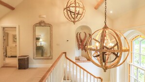 A spacious foyer with a high ceiling, a grand staircase with wooden railings, and a large mirror reflecting the room. - Fern Bank (Penrith)