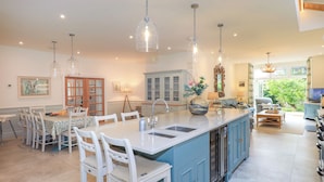 A spacious kitchen with a large island, white bar stools, and pendant lighting. - Fern Bank (Penrith)