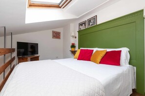 Une chambre à coucher avec un lit, un téléviseur, une tête de lit verte et un puits de lumière.