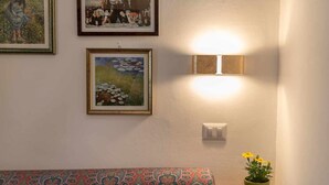A room with a patterned bench, a wall-mounted light fixture, and a framed painting above it. - Corallo studio mezzanine (Spello)