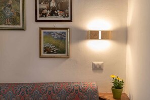 A cozy corner with a bench, wall-mounted light, and a beautiful painting.