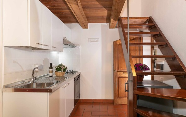 Kitchen features a gas stove, microwave, and sink, with a staircase leading to an upper level.