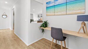 A modern interior with a wooden desk, a grey chair, a wall-mounted mirror, and a large beach-themed painting. - OSCAR -  A Tranquil Armstrong Creek Home + NETFLIX (Armstrong Creek)