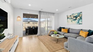 A modern living room with a grey sofa, a coffee table, and a painting on the wall. - OSCAR -  A Tranquil Armstrong Creek Home + NETFLIX (Armstrong Creek)