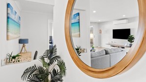 A modern living room with a large mirror, a flat-screen TV, and a grey sofa. - OSCAR -  A Tranquil Armstrong Creek Home + NETFLIX (Armstrong Creek)