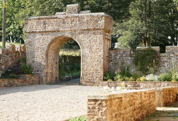 Un arco de piedra con un camino de grava que lo atraviesa.