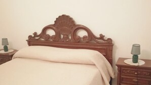 A bedroom with a wooden bed, a bedside table with a lamp, and a small bedside table with a lamp. - Vacation House La Rosa 🌹 (Trappeto)