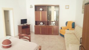 A dining area with a table, chairs, a cabinet with glass doors, and a television on a stand. - Vacation House La Rosa 🌹 (Trappeto)