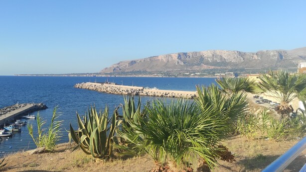 A coastal view with boats docked at a pier, a rocky breakwater, and a mountain in the background. - Vacation House La Rosa 🌹 (Trappeto)