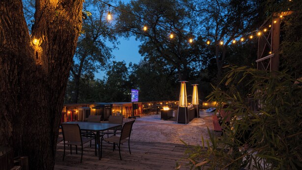 An outdoor patio with wooden tables and chairs, string lights, and a fire pit. - 《Best Austin Location ❤Huge Patio w HEATED Cowboy Pool & 65" TV❤ Skyline Views》 (Austin)