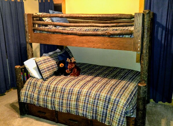 A bunk bed with a plaid bedspread and pillows, a stuffed moose toy, and a wooden headboard. - Cozy Creekside Cottage - RELAX by the Creek (Sapphire)