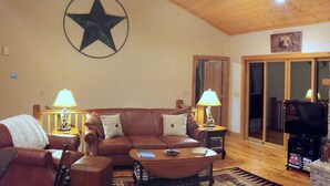 A cozy living room with a leather sofa, a coffee table, a fireplace, and a television.
