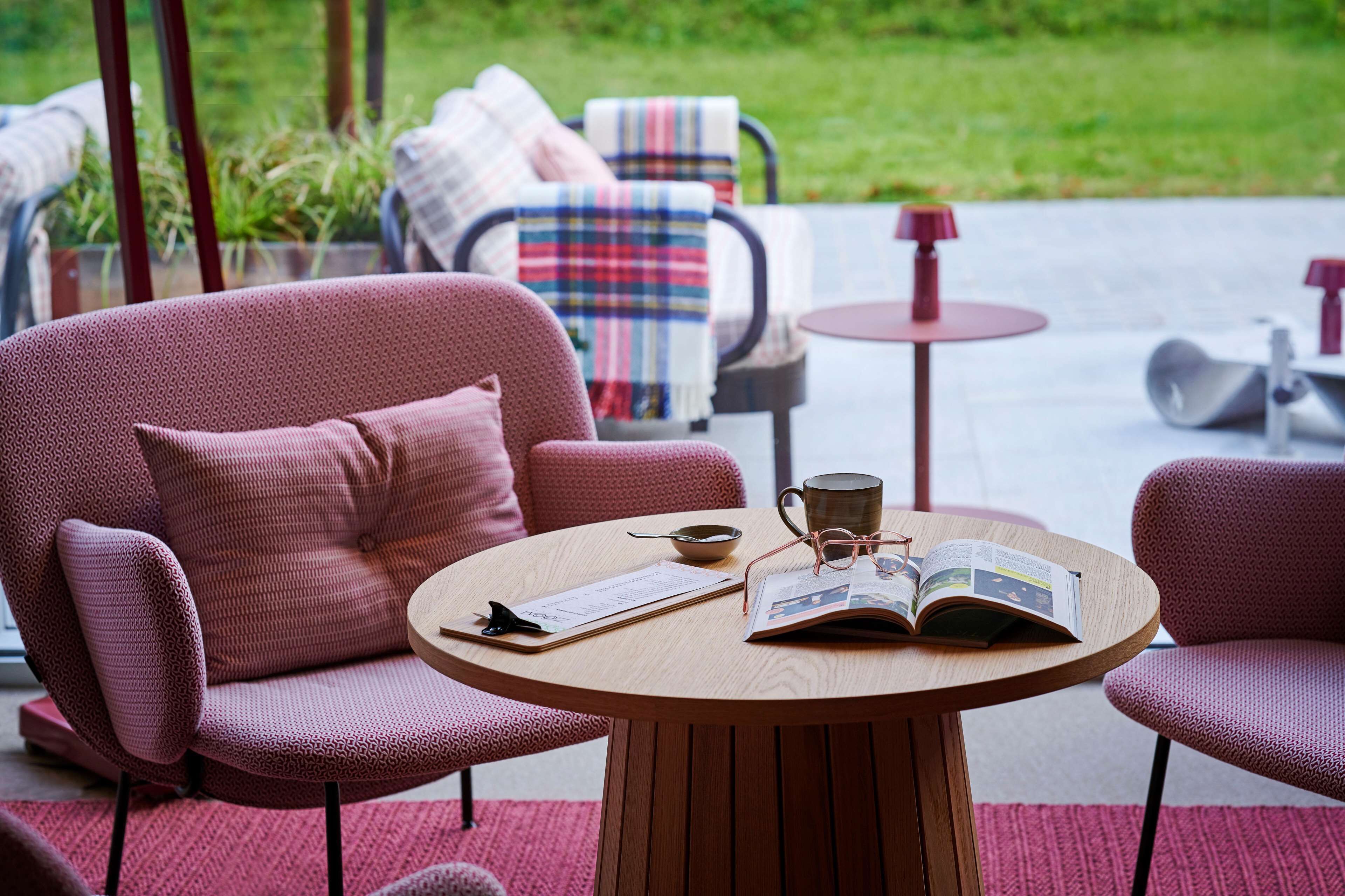 A cozy seating area with a round wooden table, a red patterned sofa, and a matching armchair.