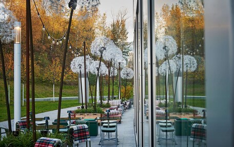 An outdoor seating area with tables and chairs, surrounded by trees and plants.