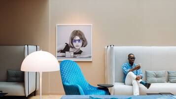A modern living room with a sofa, a blue armchair, and a floor lamp.