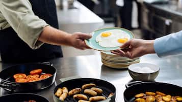 A breakfast buffet with various cooked foods like eggs, sausages, and tomatoes.