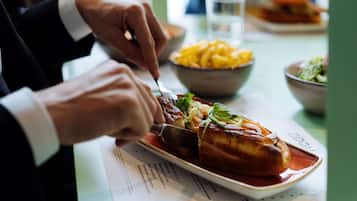 A person cutting a sandwich on a plate with a fork and knife.