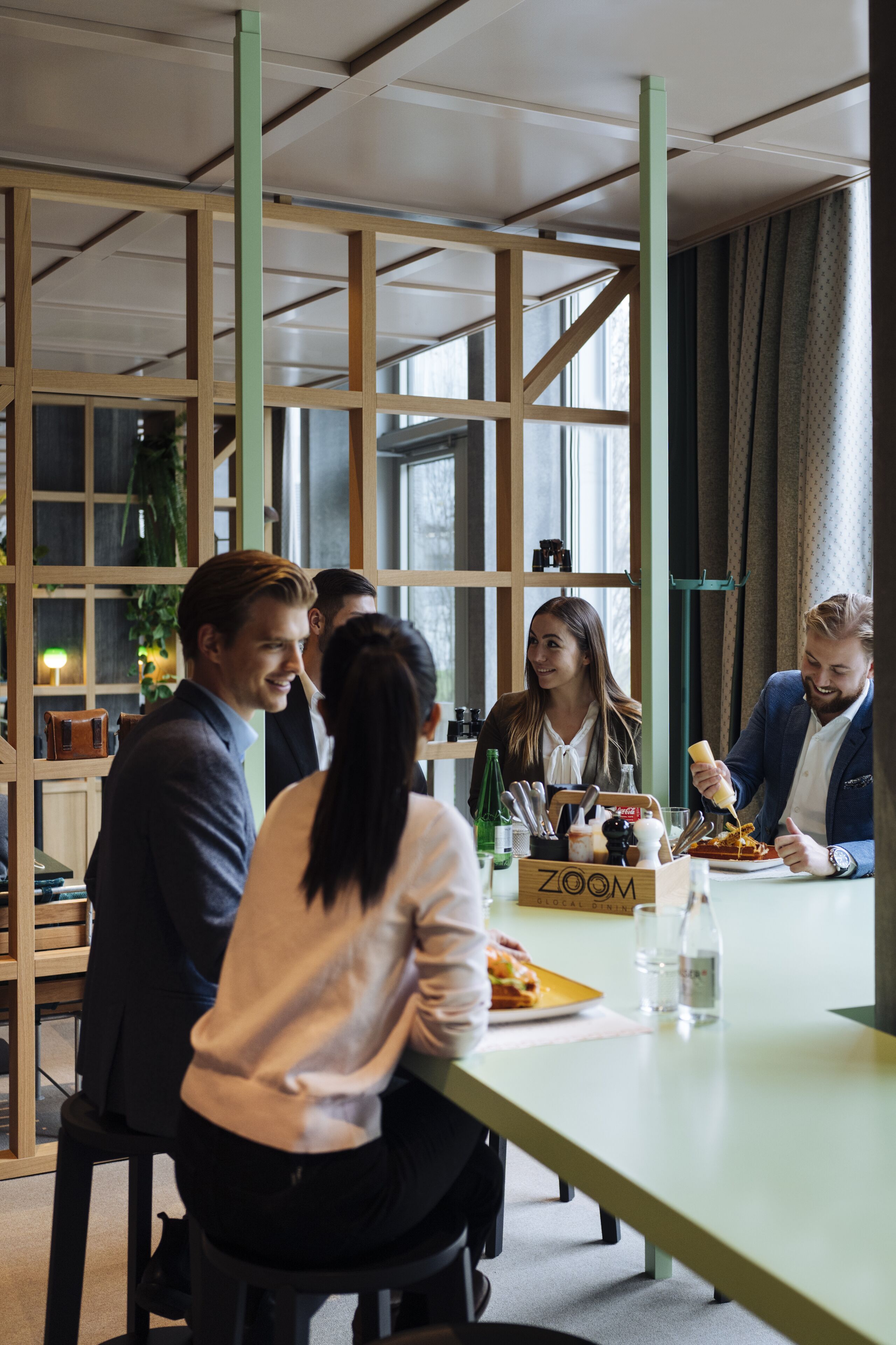 A modern meeting room with a long table, wooden partitions, and large windows.