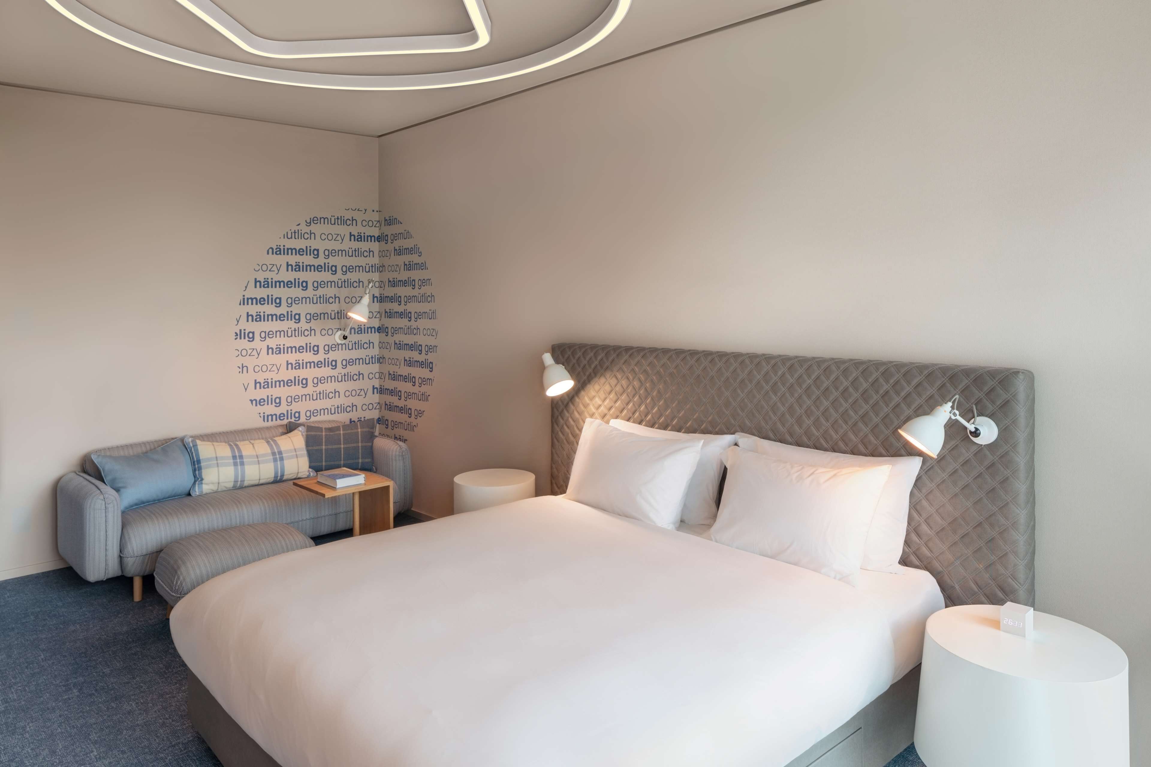 Ein modernes Hotelzimmer mit einem großen Bett, einer Couch und einem Nachttisch.