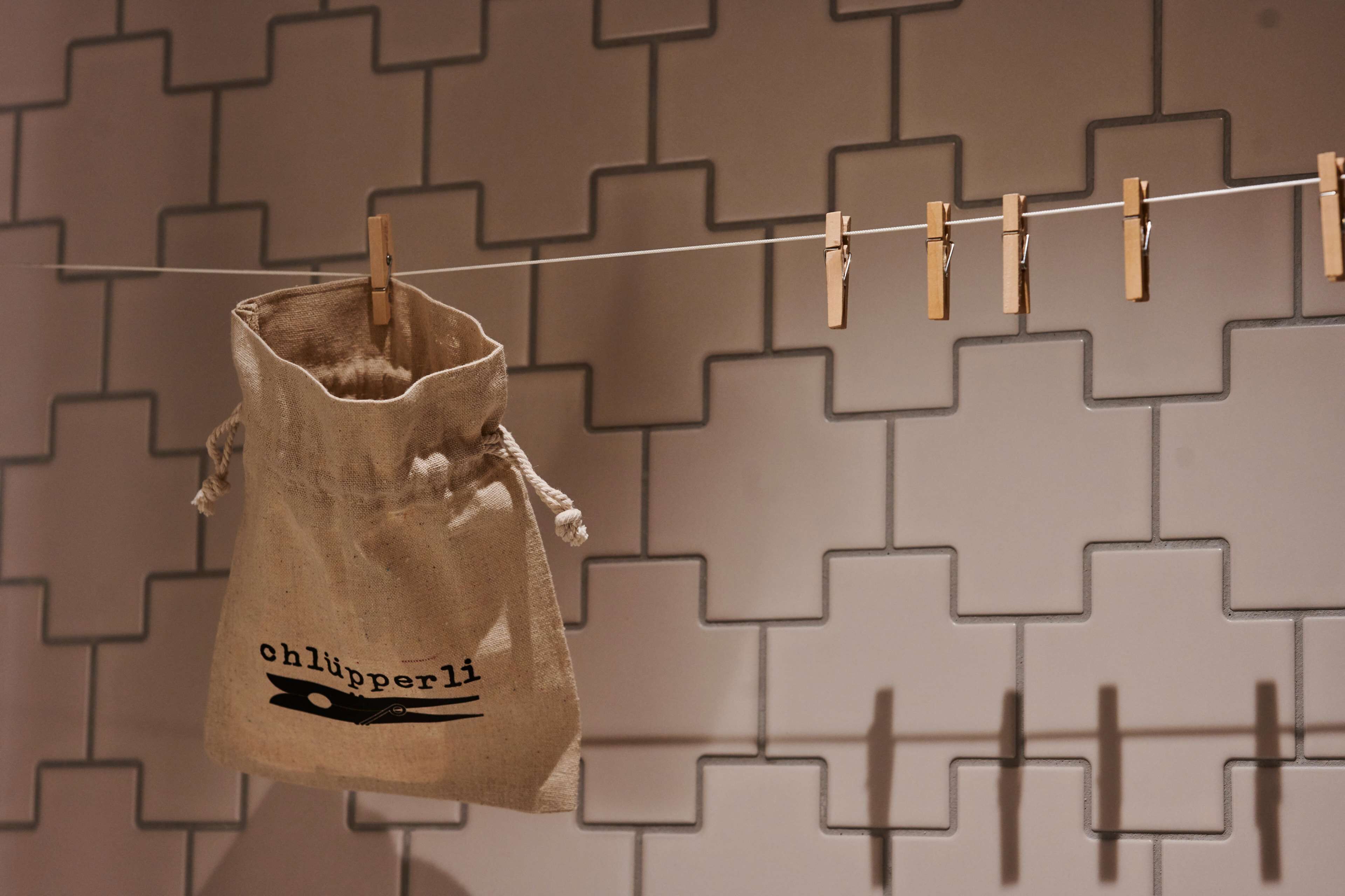 A clothespin bag hanging on a line with a geometric patterned wall in the background.