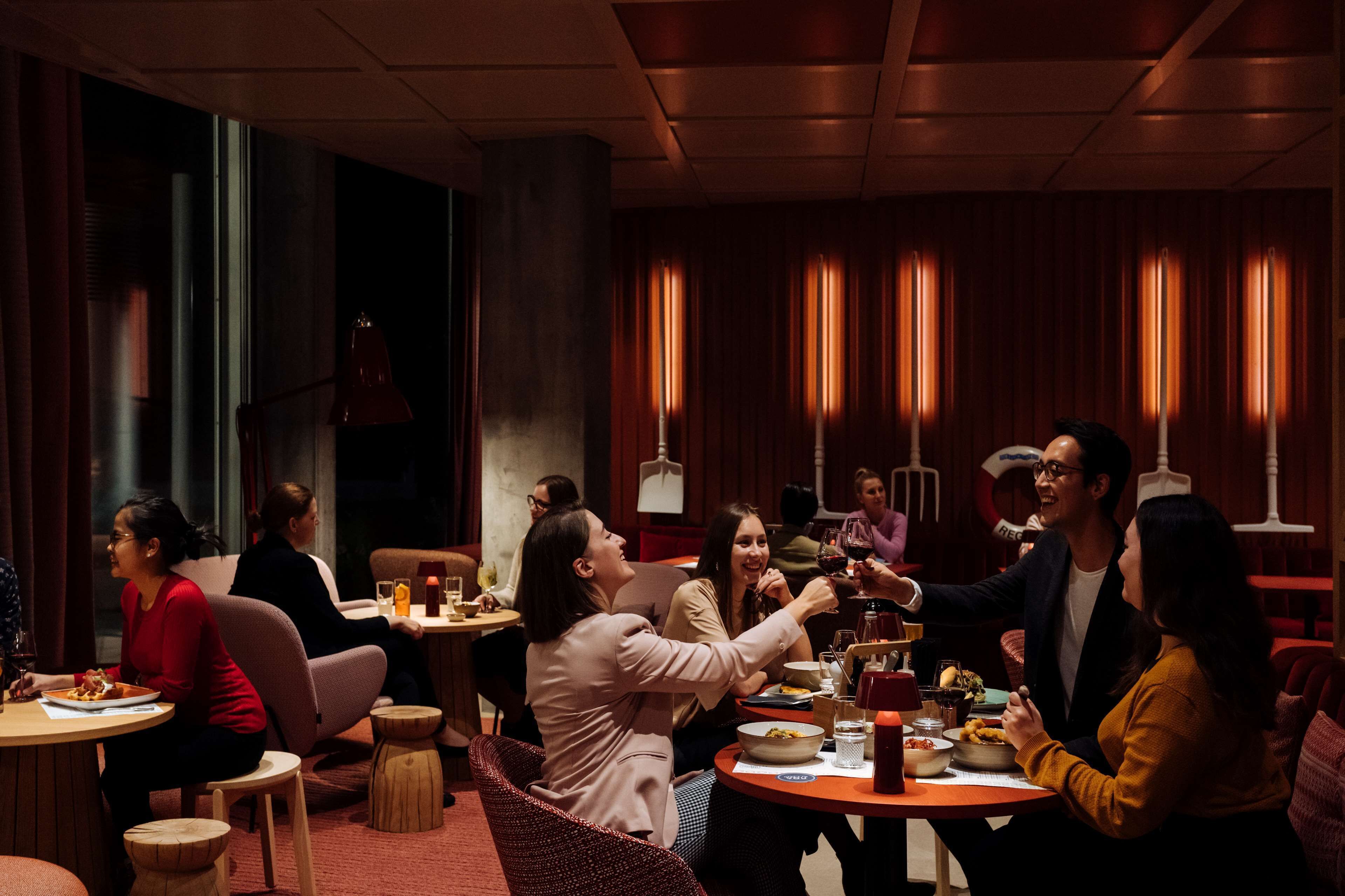 Un restaurante con mesas redondas, taburetes de madera e iluminación cálida.