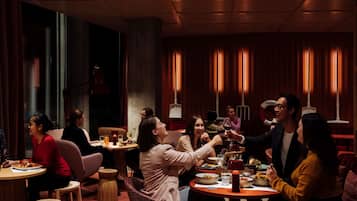 A restaurant with round tables, wooden stools, and warm lighting.