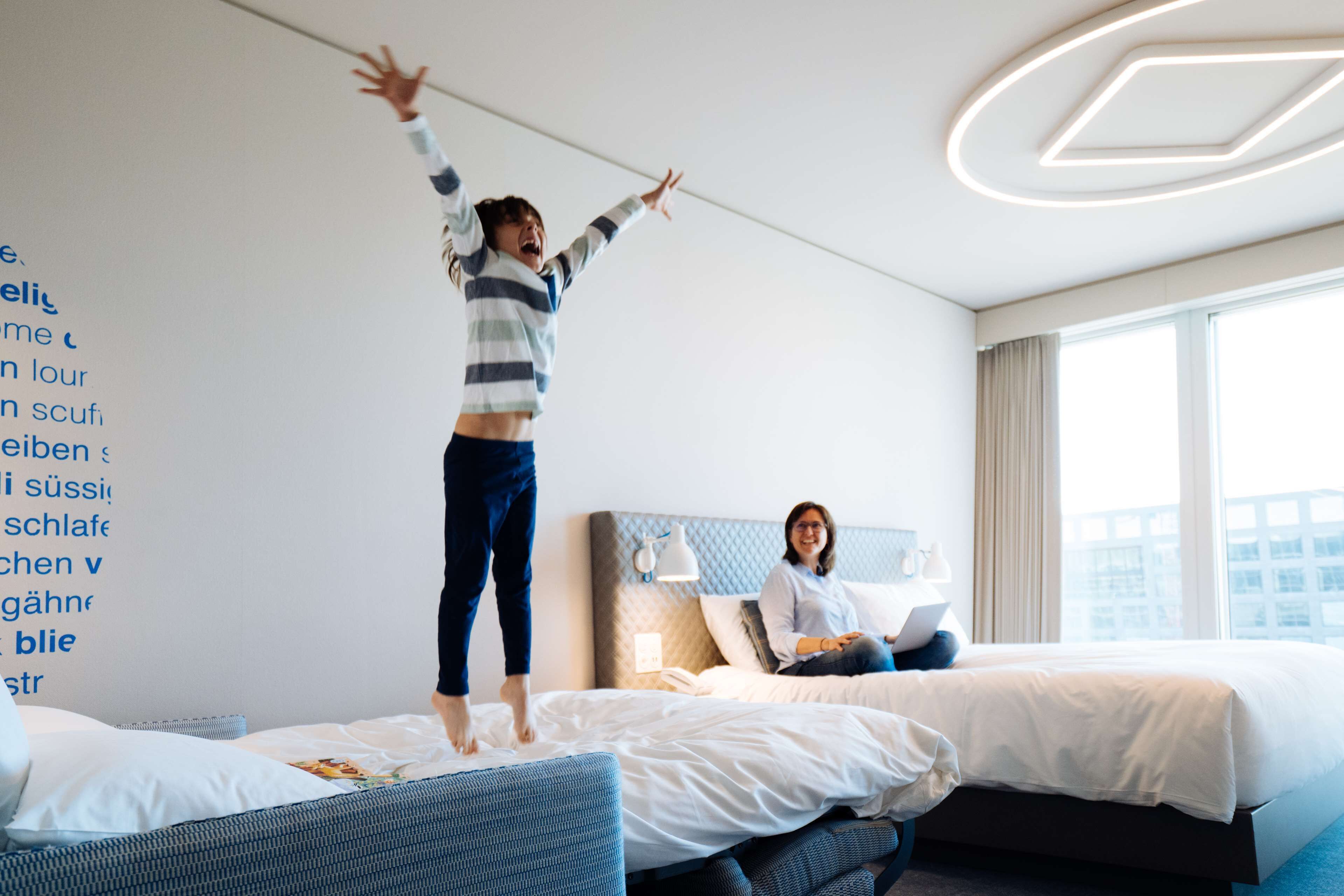Una habitación de hotel con dos camas, un ventanal grande y una pared con texto.