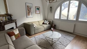 Un salón espacioso con un amplio sofá modular, una mesa redonda de centro y vistas a través de un gran ventanal de arco.