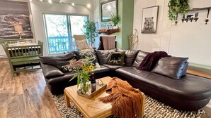Un salon moderne avec un canapé d’angle, une table basse en bois et une grande fenêtre laissant entrer la lumière naturelle.