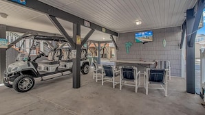 A covered outdoor area with a table and chairs, a vehicle, and a sign that reads "Welcome to Paradise." - COCONUT TREEHOUSE, 5 bed/3.5 bath, 1 minute walk to beach, Holiday Inn section (Myrtle Beach)