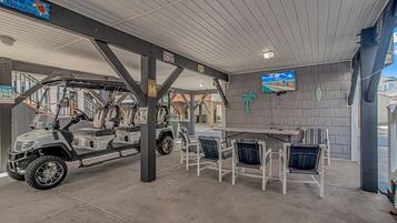 A covered outdoor area with a table and chairs, a vehicle, and a sign that reads "Welcome to Paradise."